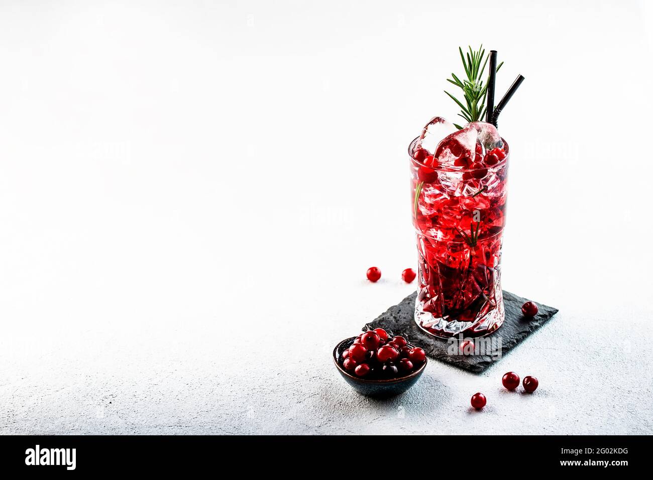 Cranberry, vodka, gin alcoholic cocktail with ice, rosemary and berries