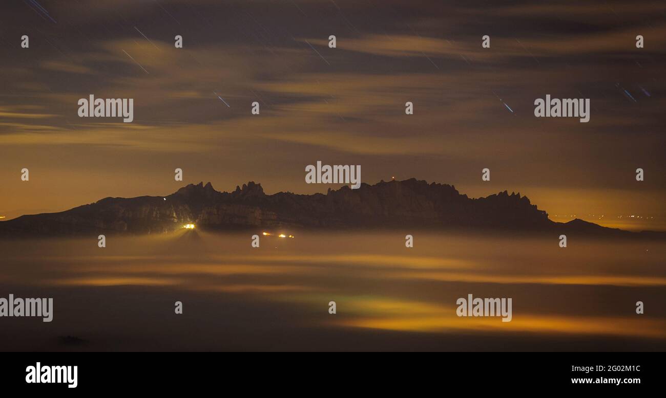 Montserrat mountain at night above a sea of clouds, seen from the Turó de la Pola summit (Barcelona, Catalonia, Spain) Stock Photo