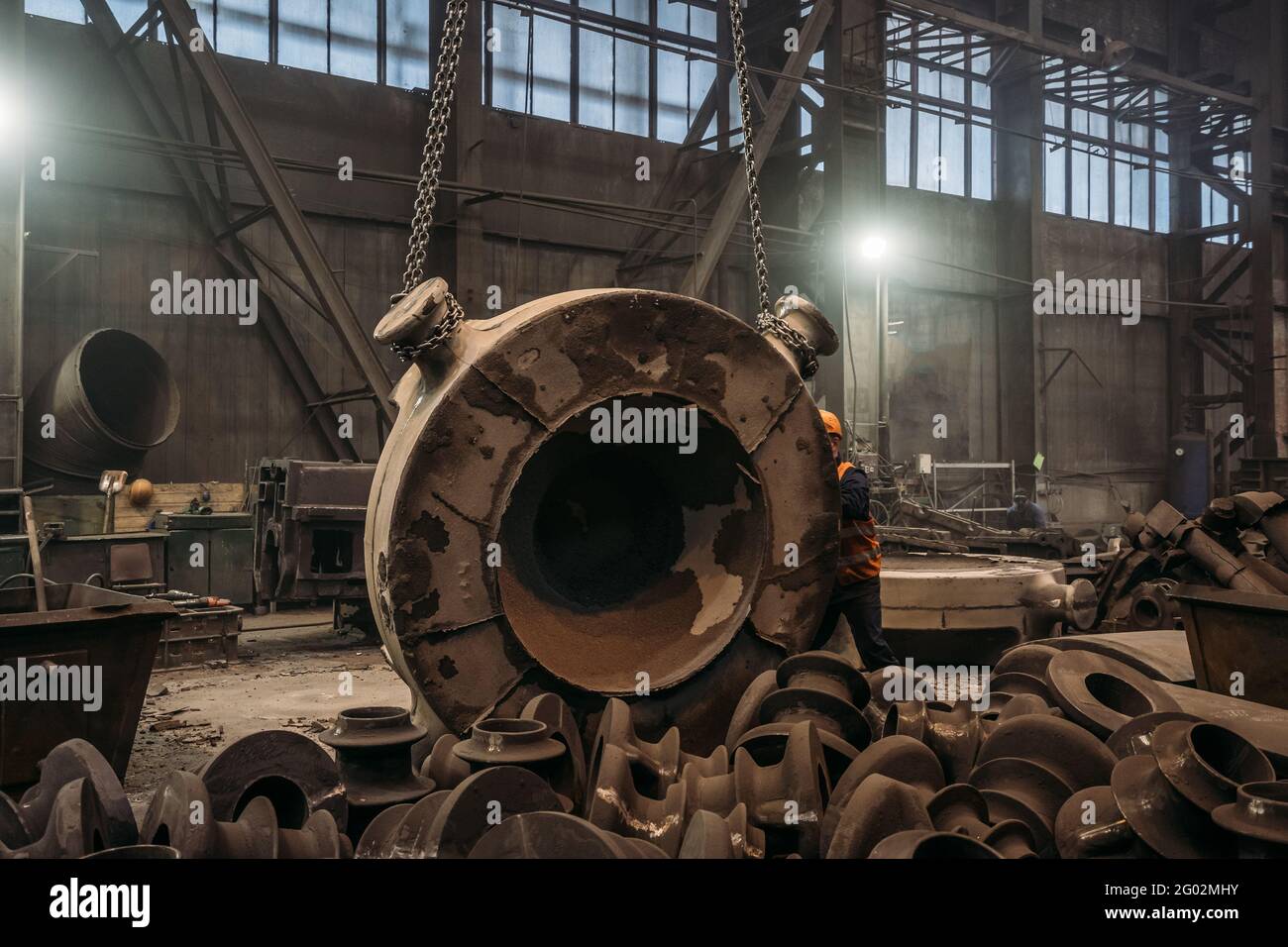 Large cast iron product moved on girder crane in workshop of metallurgical plant. Foundry, Heavy industry, production of large iron parts. Stock Photo
