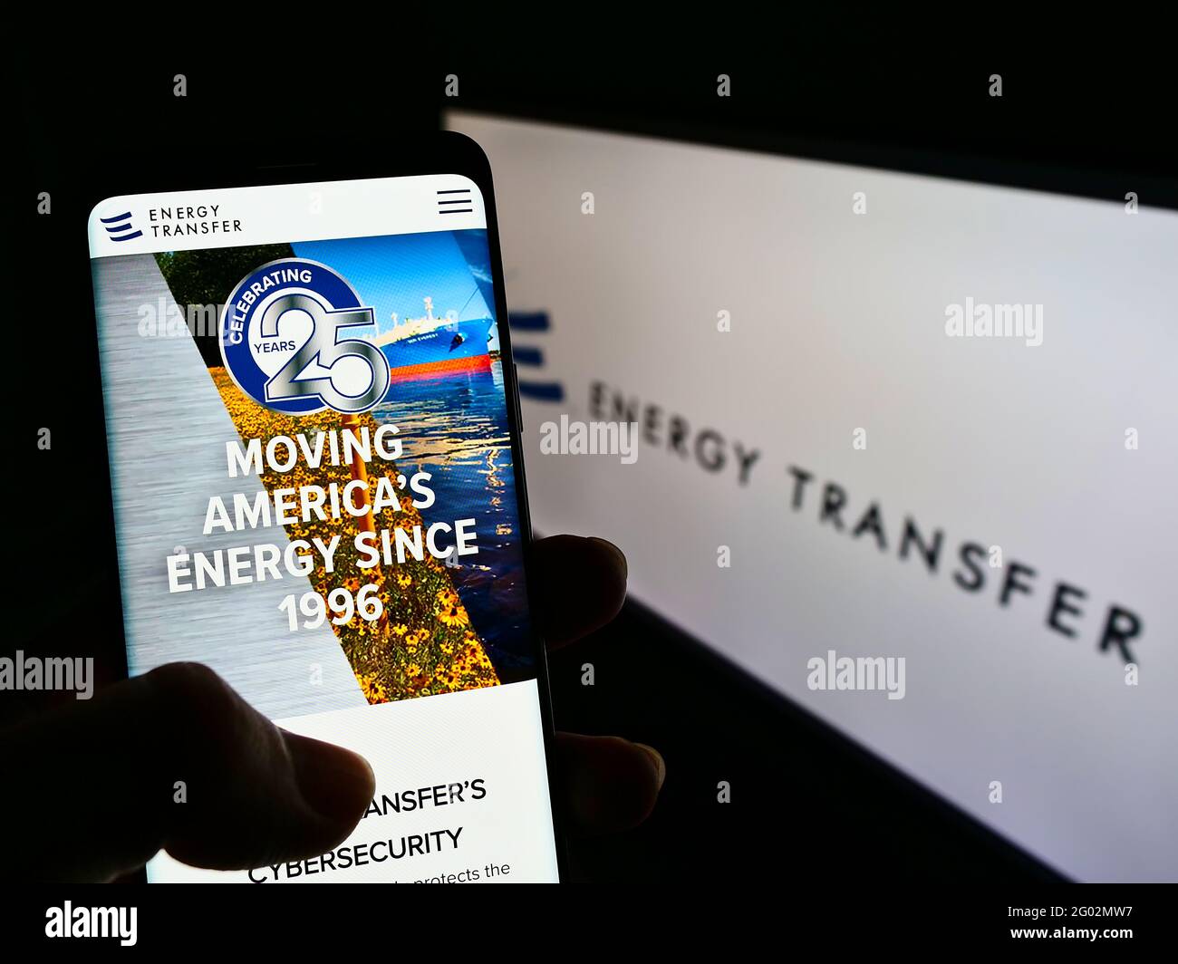 Person holding mobile phone website logo of US pipeline company Energy Transfer LP on screen in front of logo. Focus on center of phone display. Stock Photo