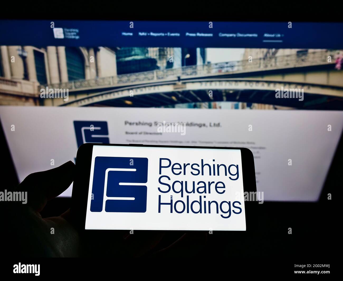 Person holding smartphone with logo of company Pershing Square Capital Management L.P. on screen in front of website. Focus on phone display. Stock Photo