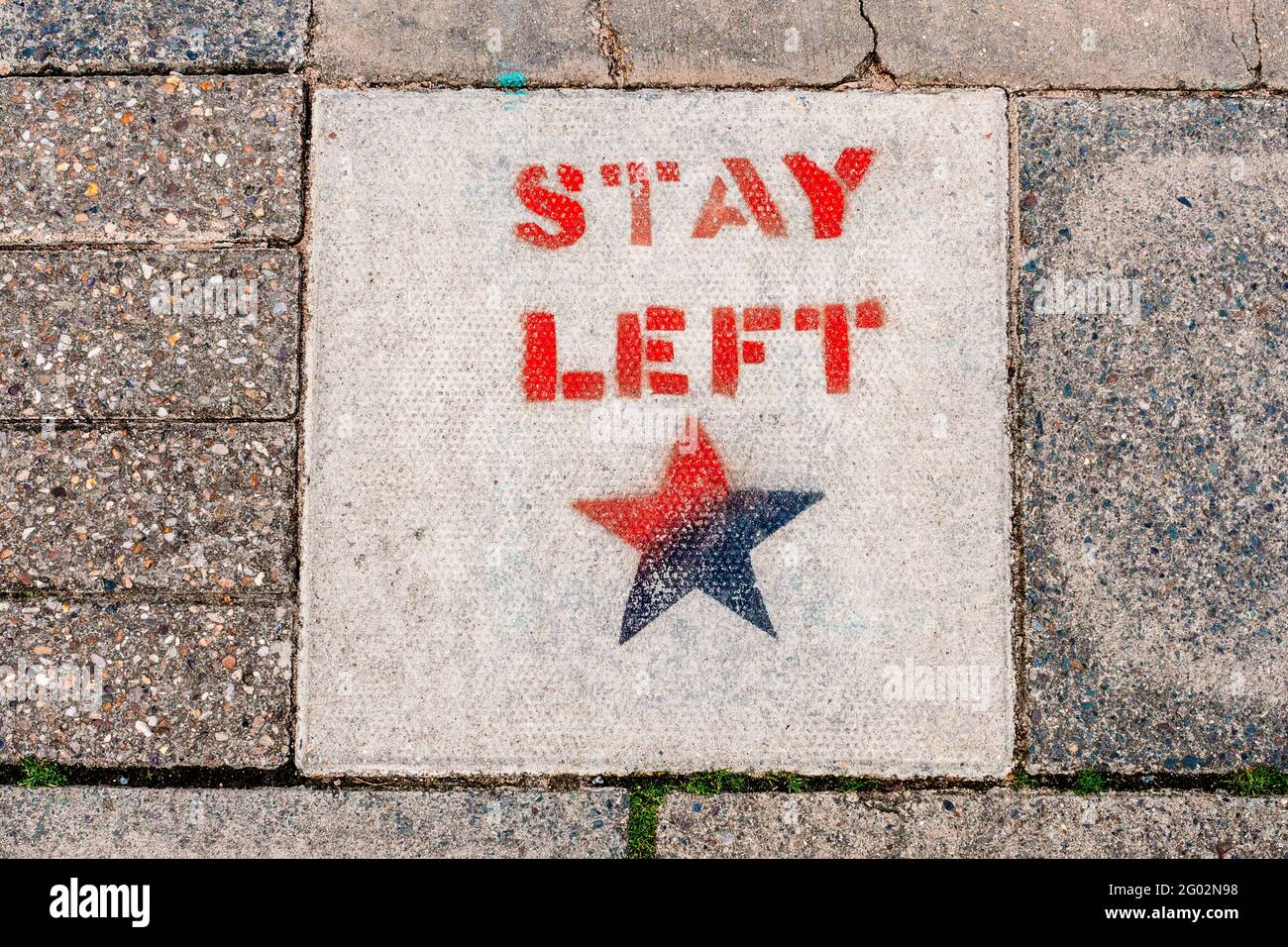 Stay Left - political graffiti created using a stencil and spray paint on a paving slab on the footpath on Mill Road Broadway, Cambridge, UK. Stock Photo