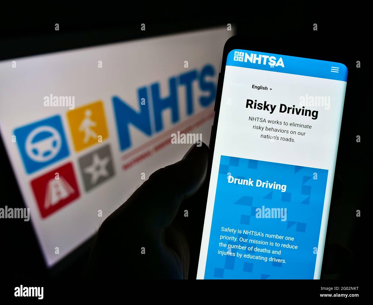 Person holding cellphone with website of National Highway Traffic Safety Administration (NHTSA) on screen with logo. Focus on center of phone display. Stock Photo