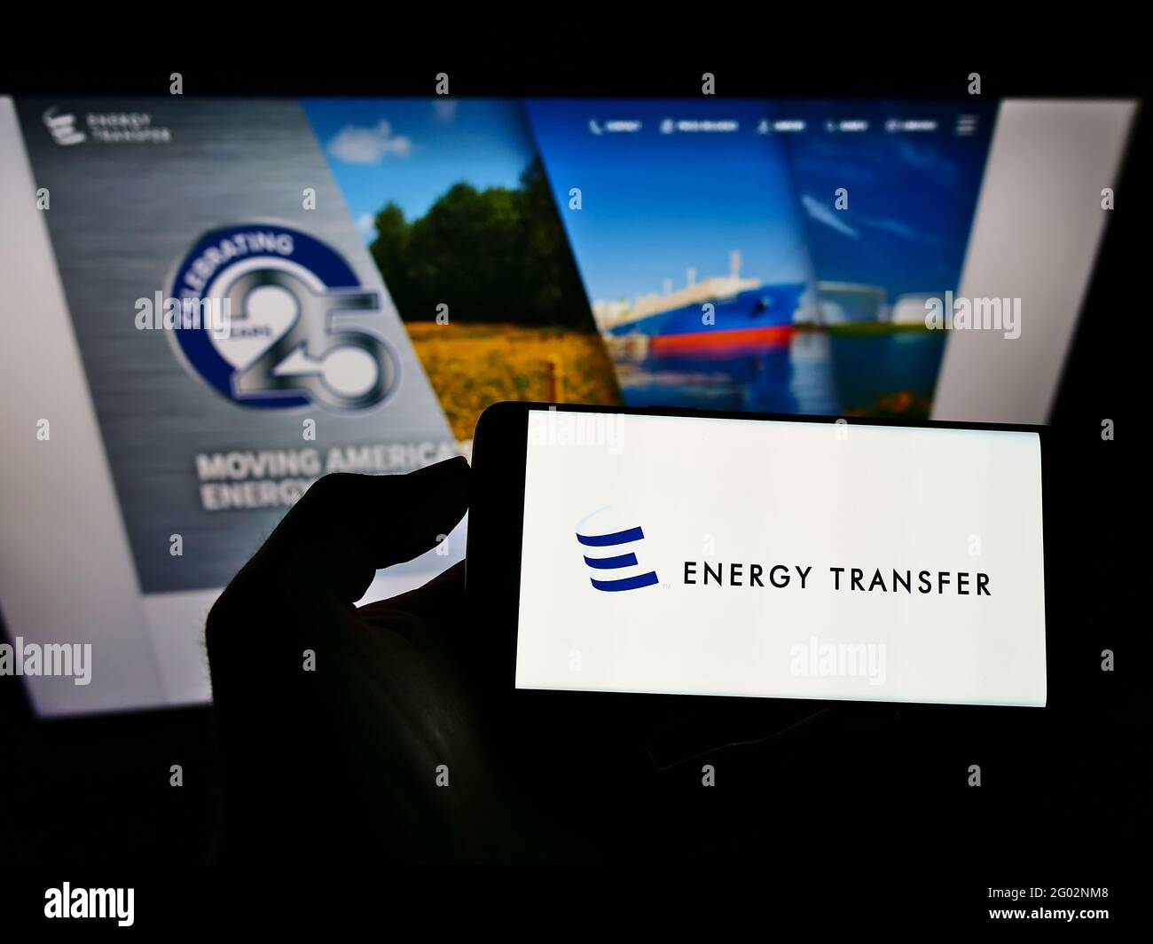 Person holding smartphone with logo of US pipeline company Energy Transfer LP on screen in front of website. Focus on phone display. Stock Photo
