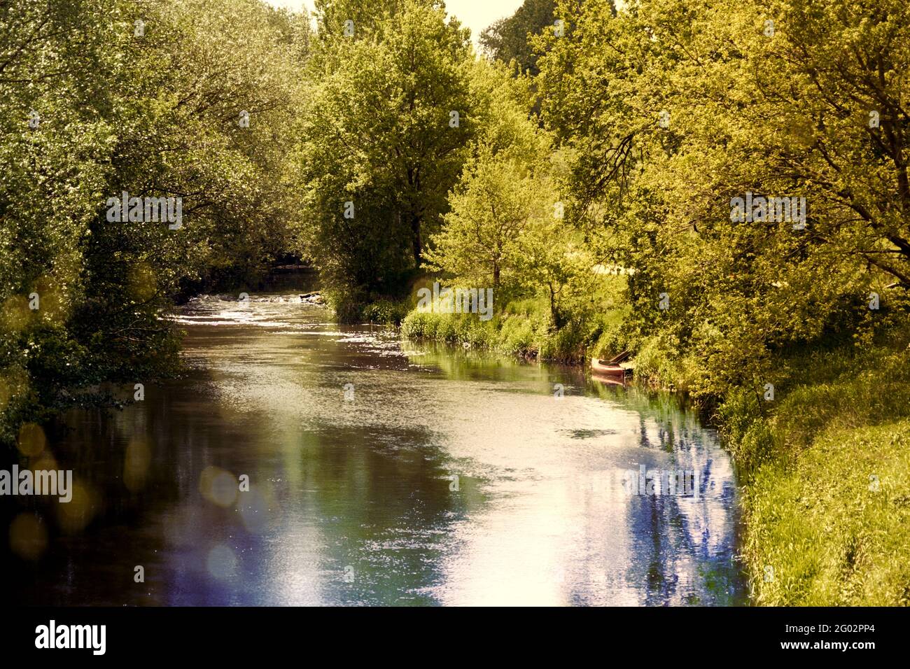 The small river Aller near Gifhorn in Germany in bright sunlight with a canoe for a boat trip, backlight with sun flare Stock Photo