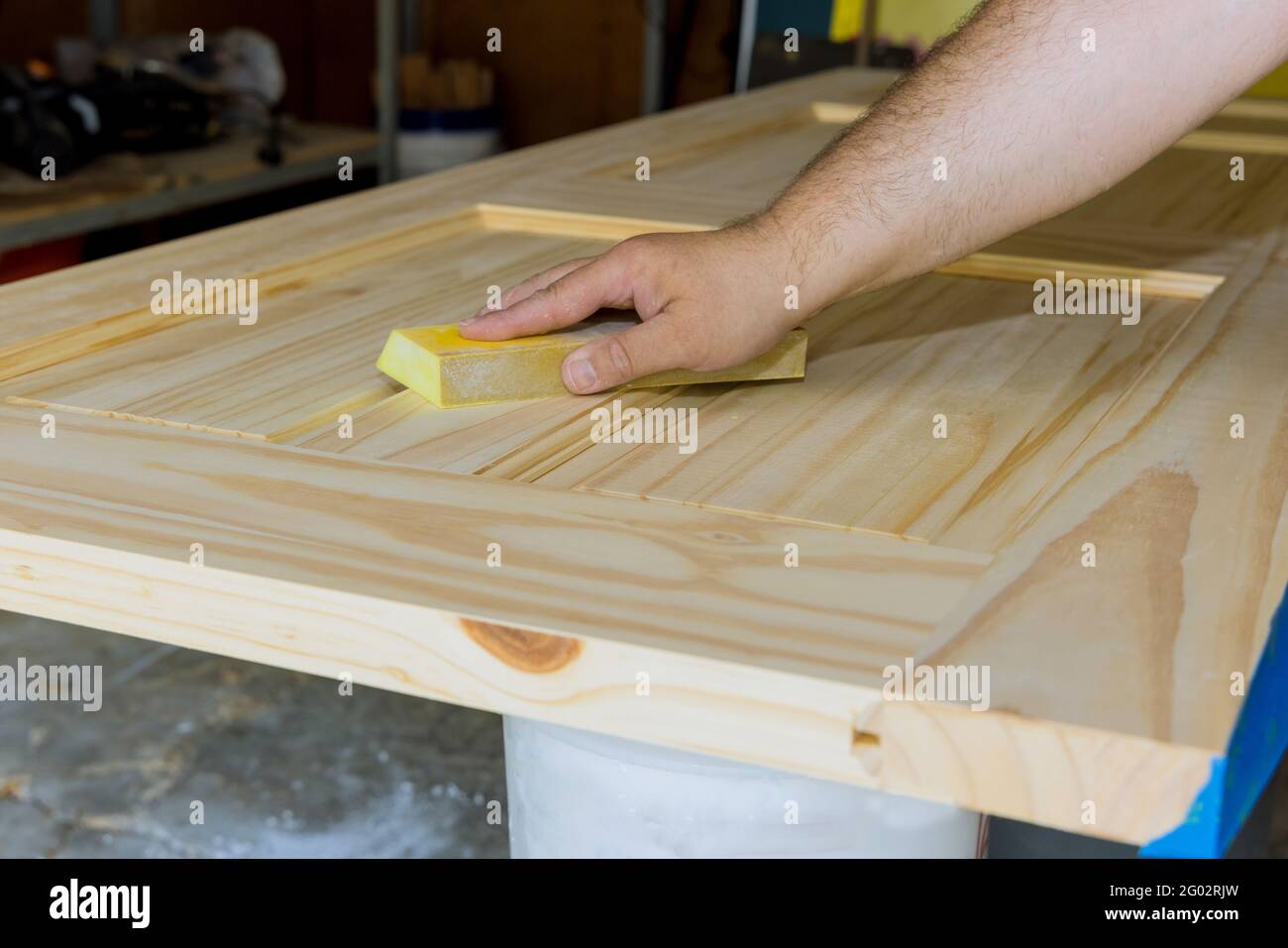 Carpenter in work on worker sanding with sanding block wooden door Stock Photo