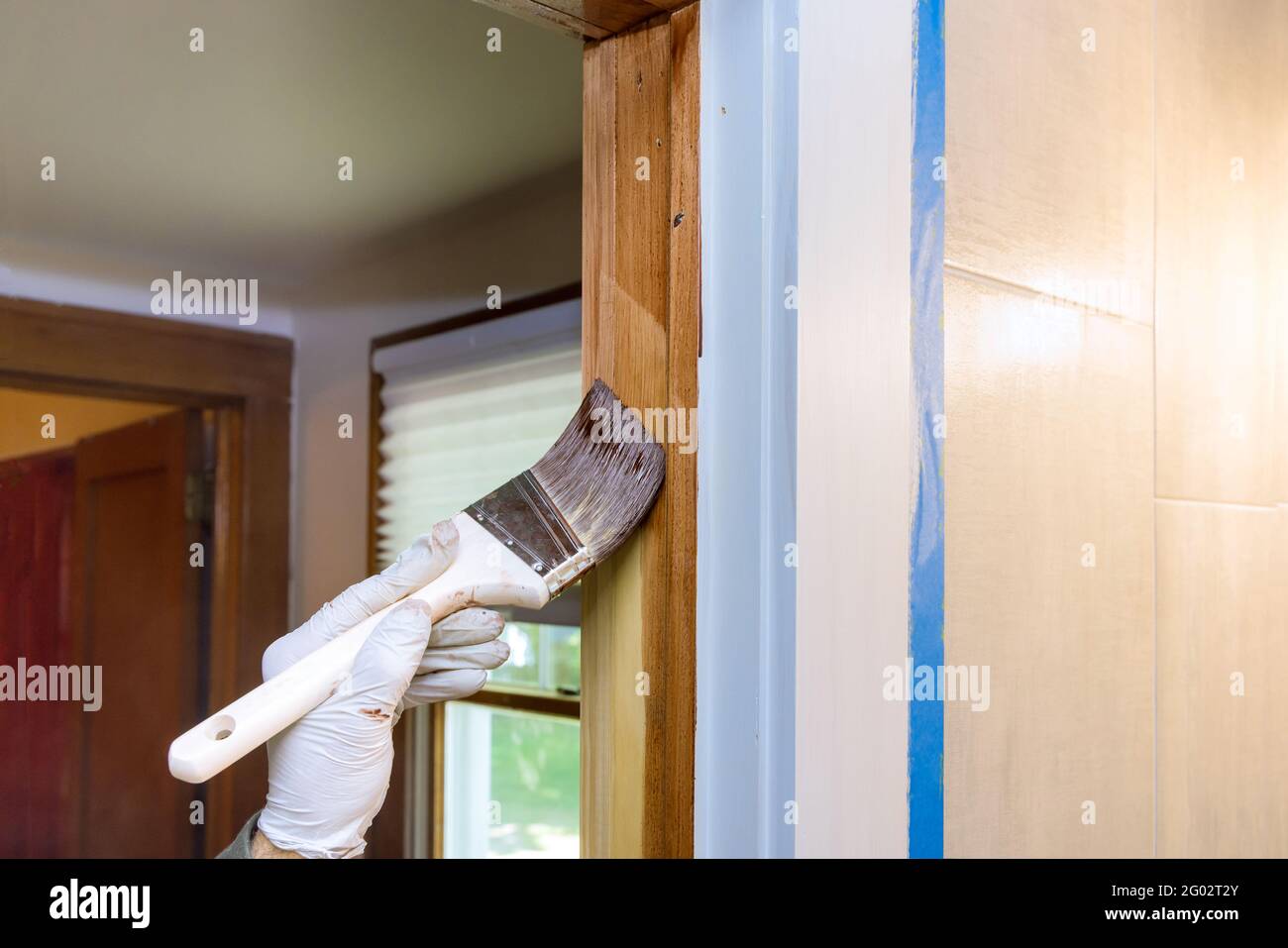 Worker hand is holding a brush painting new wooden molding trim with paintbrush Stock Photo Alamy