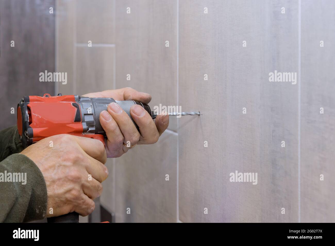 Hands of plumber using a drill to create new holes in tile bathroom Stock Photo