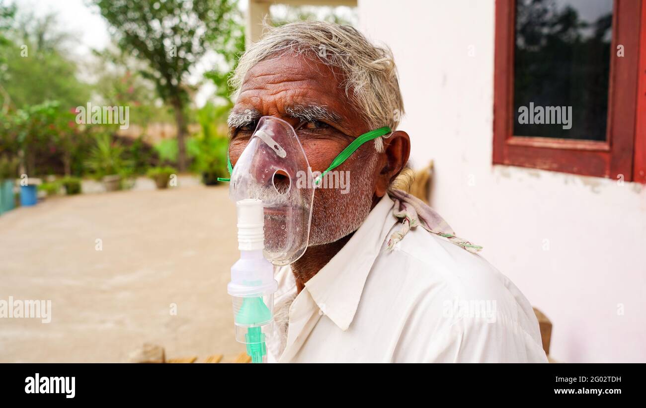 20 May 2021- Reengus, Sikar, India. A elder person infected with Covid 19 disease. Patient inhaling oxygen wearing mask with liquid Oxygen flow. Stock Photo