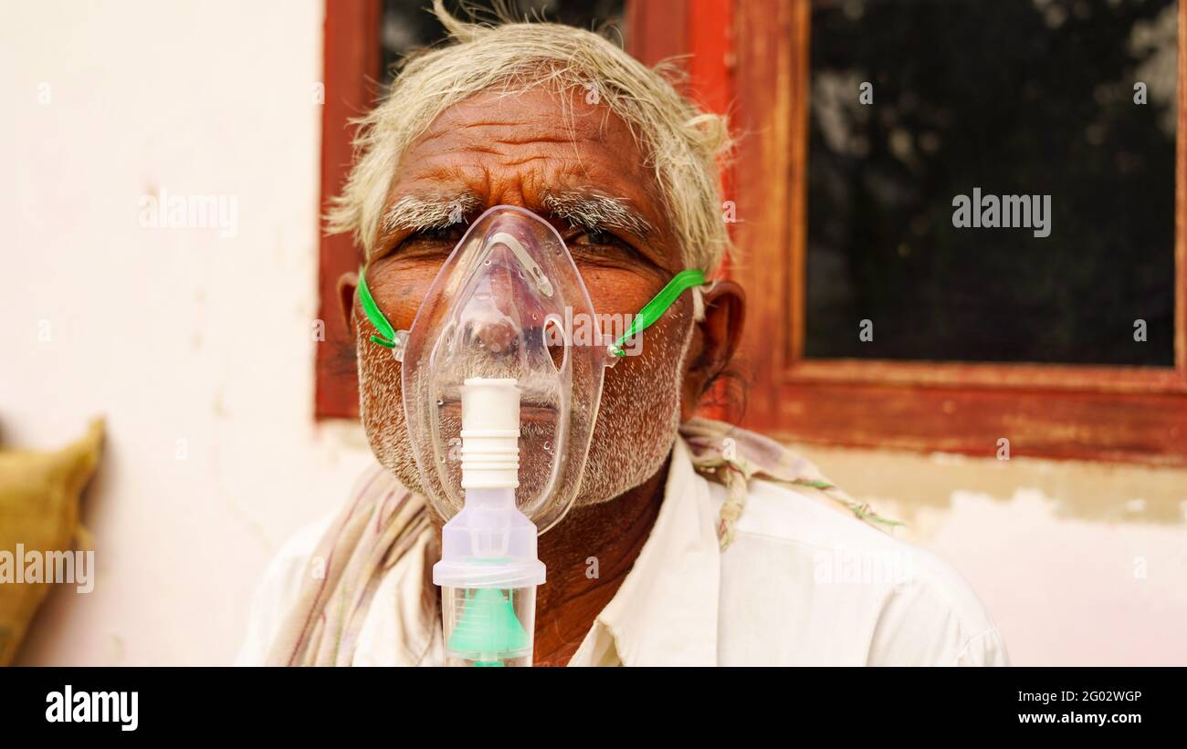 20 May 2021- Reengus, Sikar, India. A elder person infected with Covid 19 disease. Patient inhaling oxygen wearing mask with liquid Oxygen flow. Stock Photo