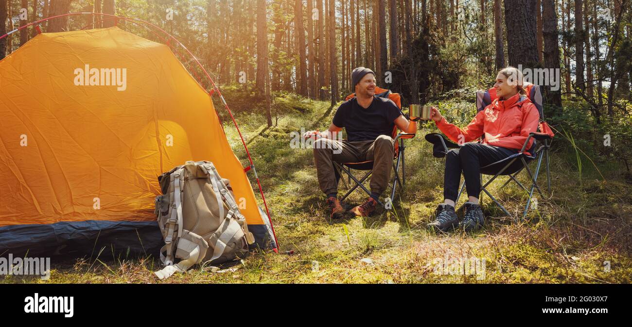 forest camping - young hiker couple enjoying cup of tee at campsite Stock Photo