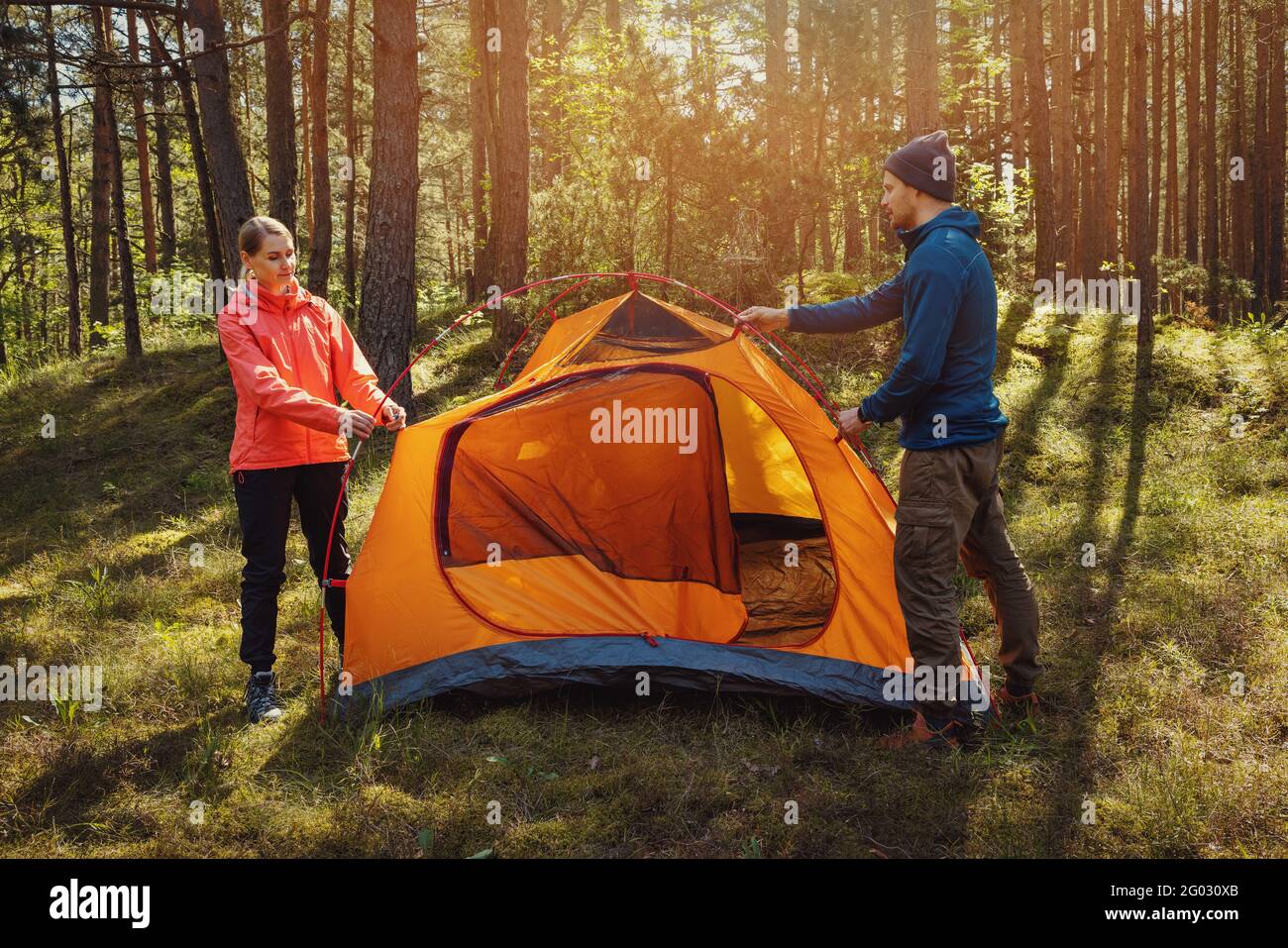 young couple set up a tent together in forest. outdoor adventure, camping trip Stock Photo