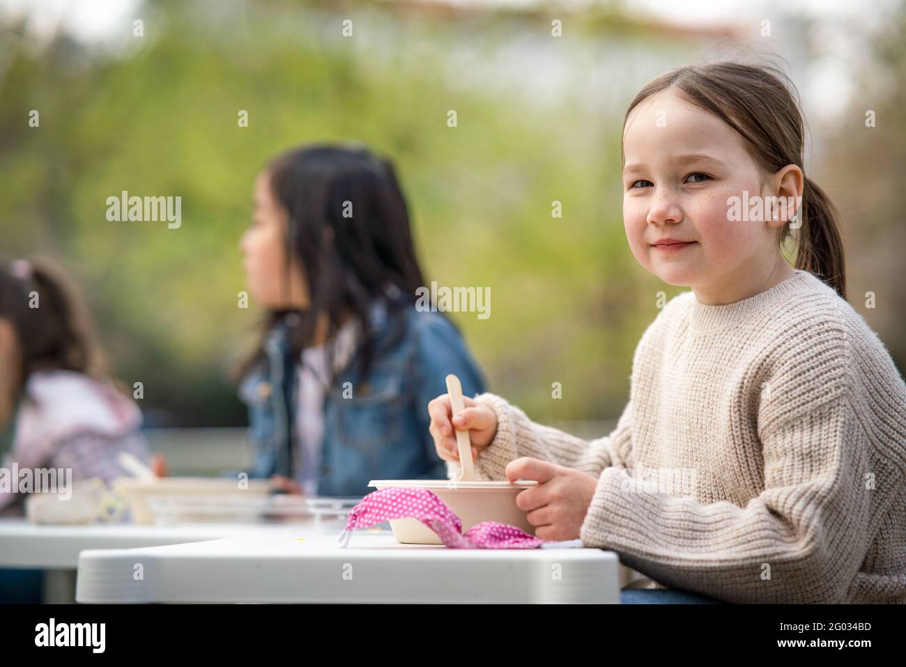 Small children eating lunch outdoors in city park, learning group education concept. Stock Photo