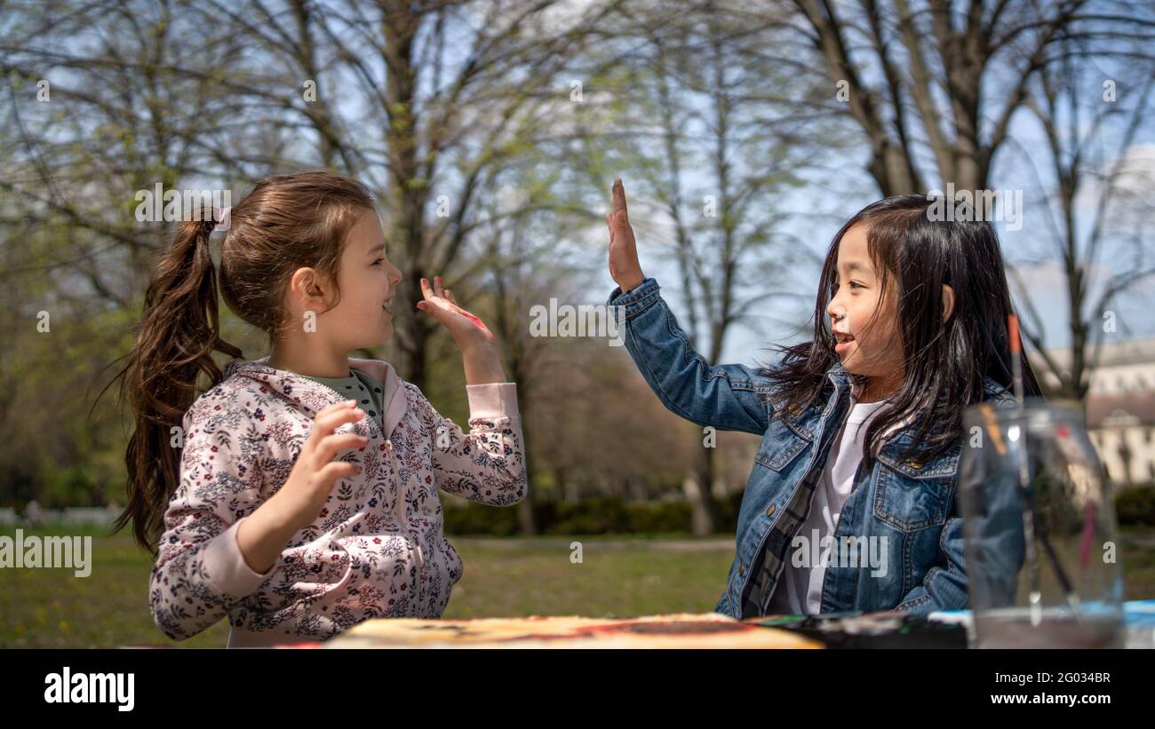 Small children painting pictures outdoors in city park, learning group education concept. Stock Photo