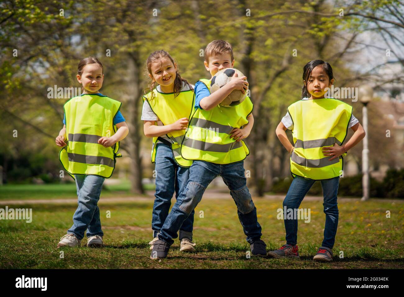 Small children with ball looking at camera outdoors in city park, learning group education concept. Stock Photo