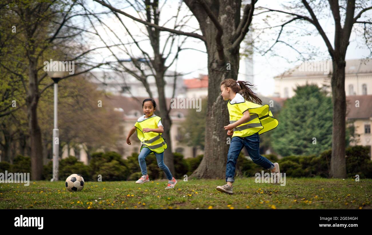 Small girls playing football outdoors in city park, learning group education concept. Stock Photo