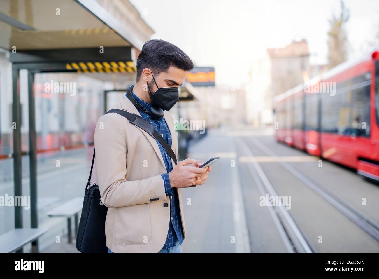 Young business man commuter with smartphone on the way to work outdoors ...