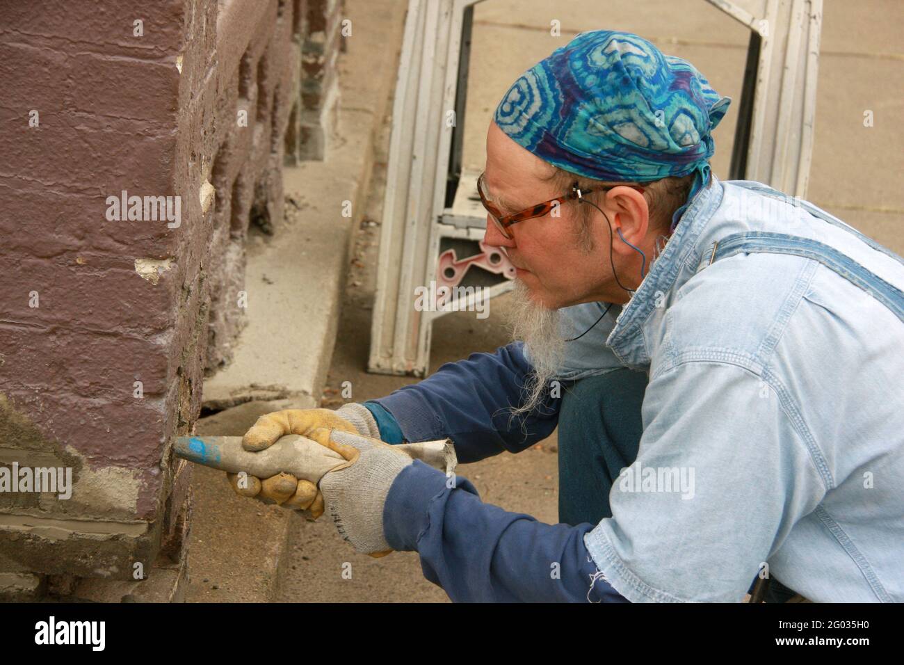Man filling in new mortar in weathered brick wall using a grout bag