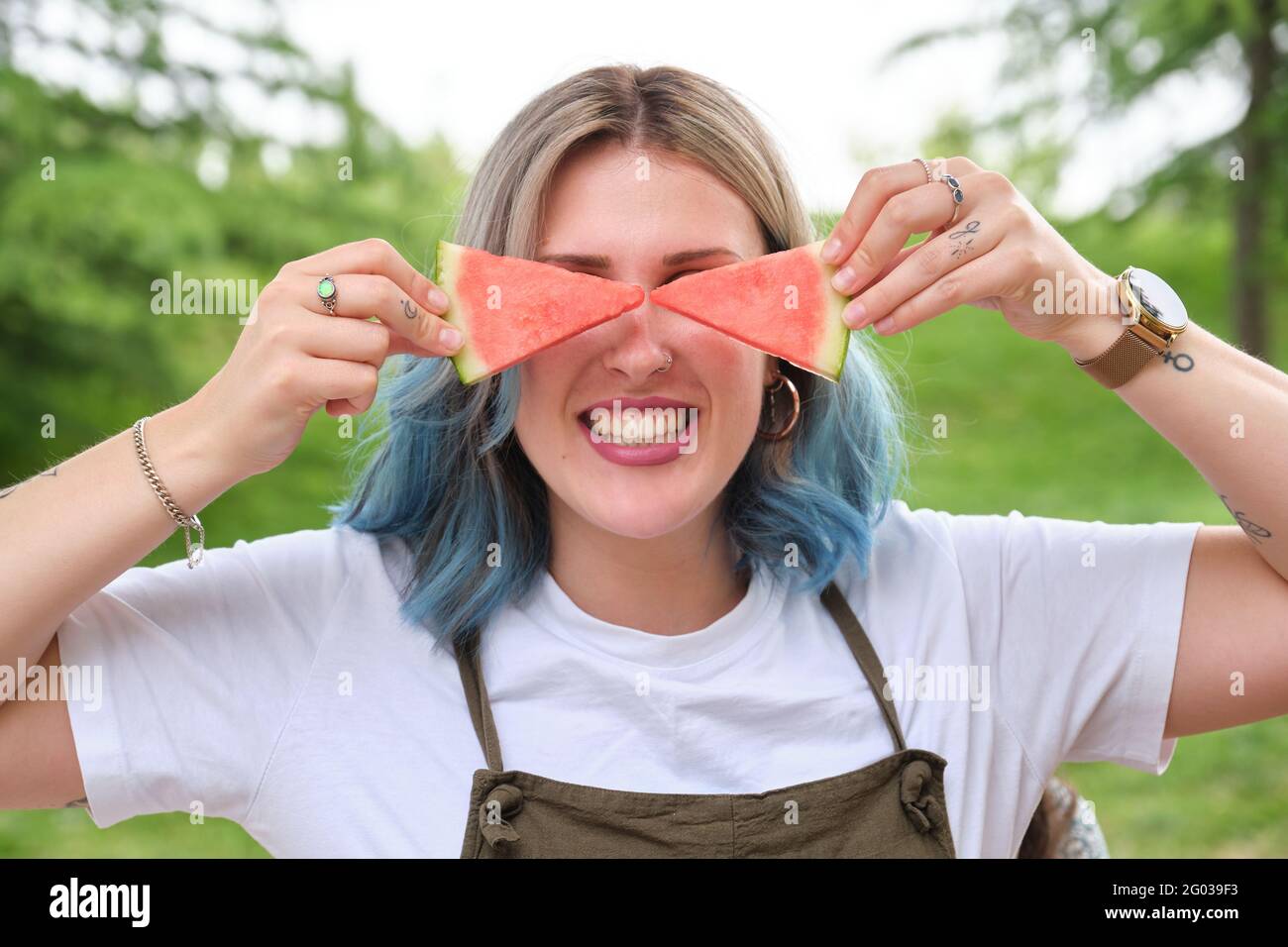 Young happy woman with watermelon slices on her eyes, having fun in a park. Picnic on a sunny summer day. Stock Photo