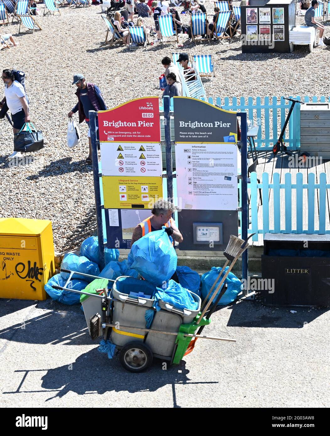 Brighton UK 31st May 2021 - A council worker cleans up as crowds on Brighton beach enjoy the Bank Holiday sunshine with temperatures expected to reach the mid twenties in parts of the South East : Credit Simon Dack / Alamy Live News Stock Photo