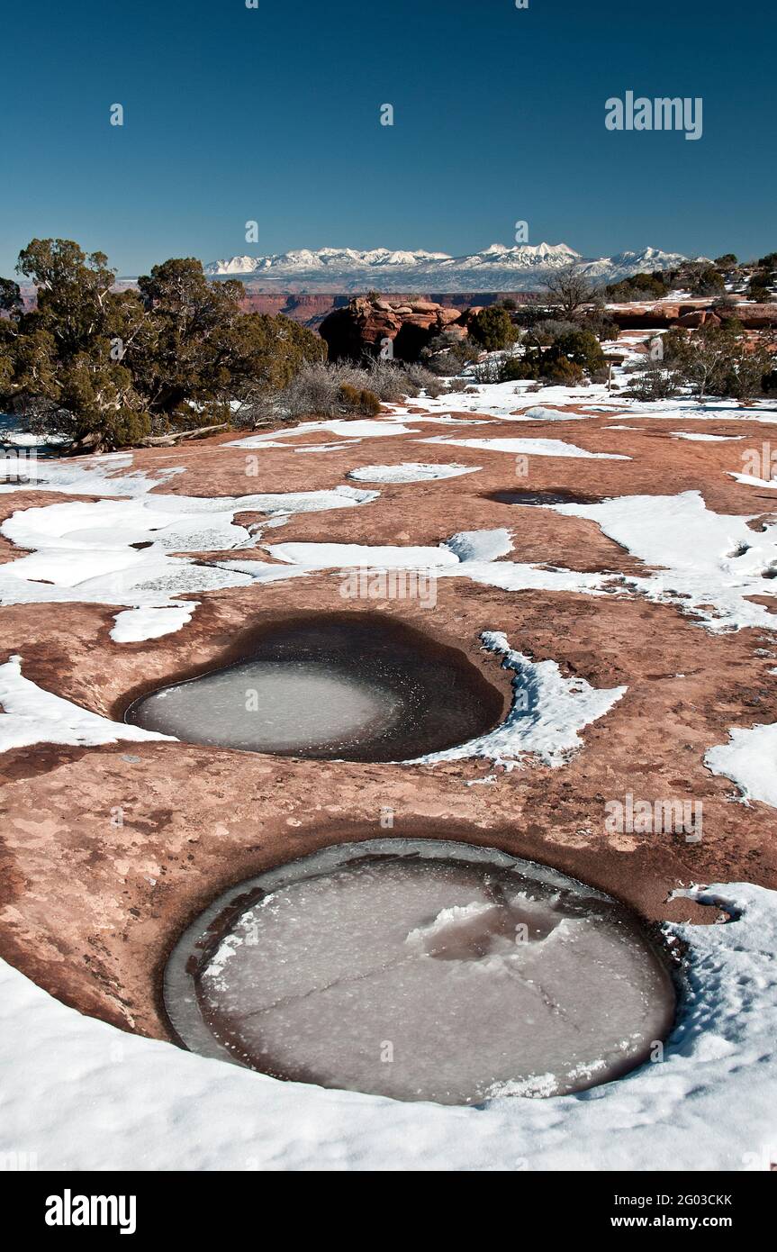 Frozen Water In Depressions In Rock Snow Capped Mountains In Distance Canyonlands National Park Utah Stock Photo Alamy
