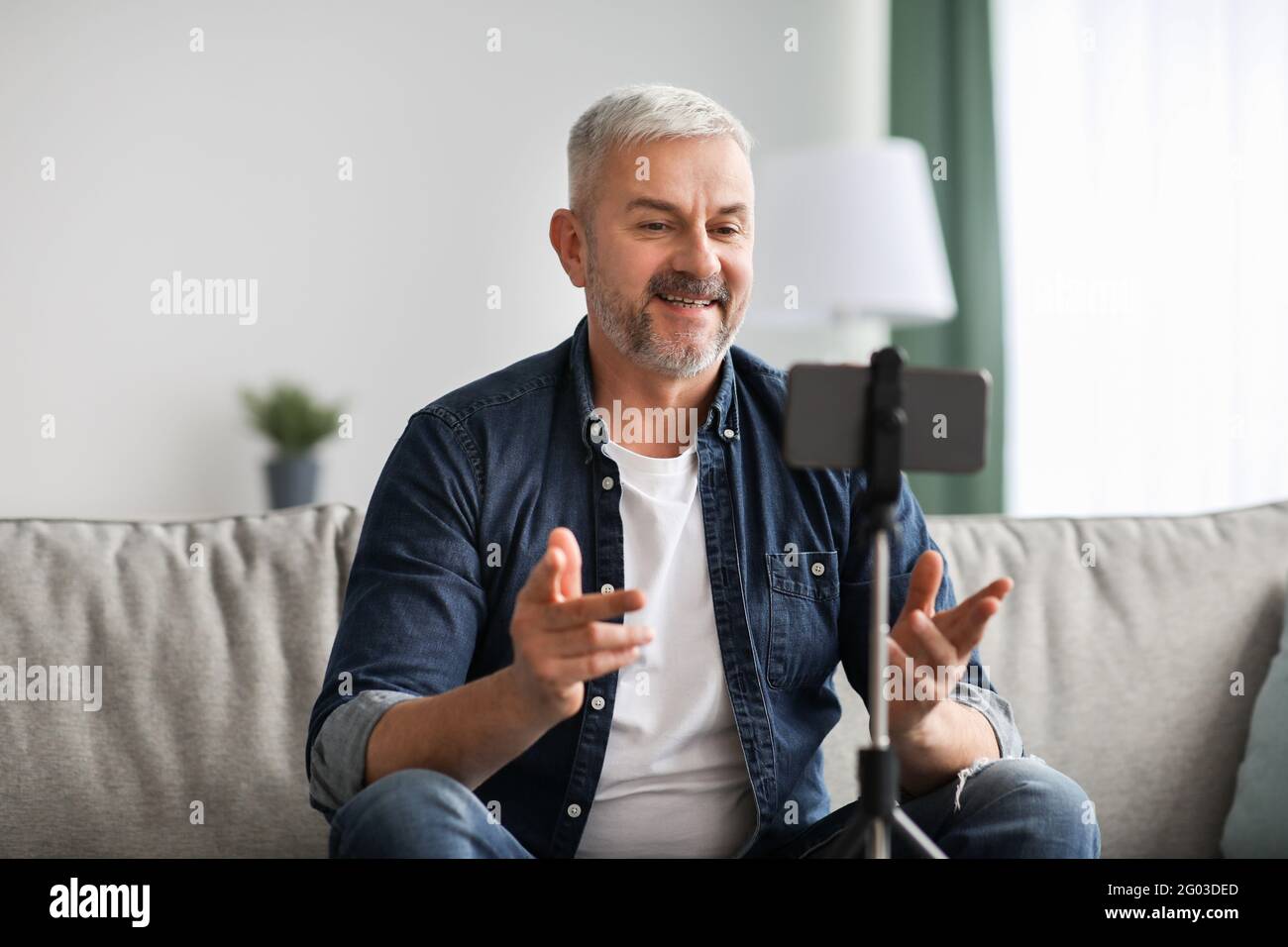 Smiling senior man vlogger broadcasting from home Stock Photo