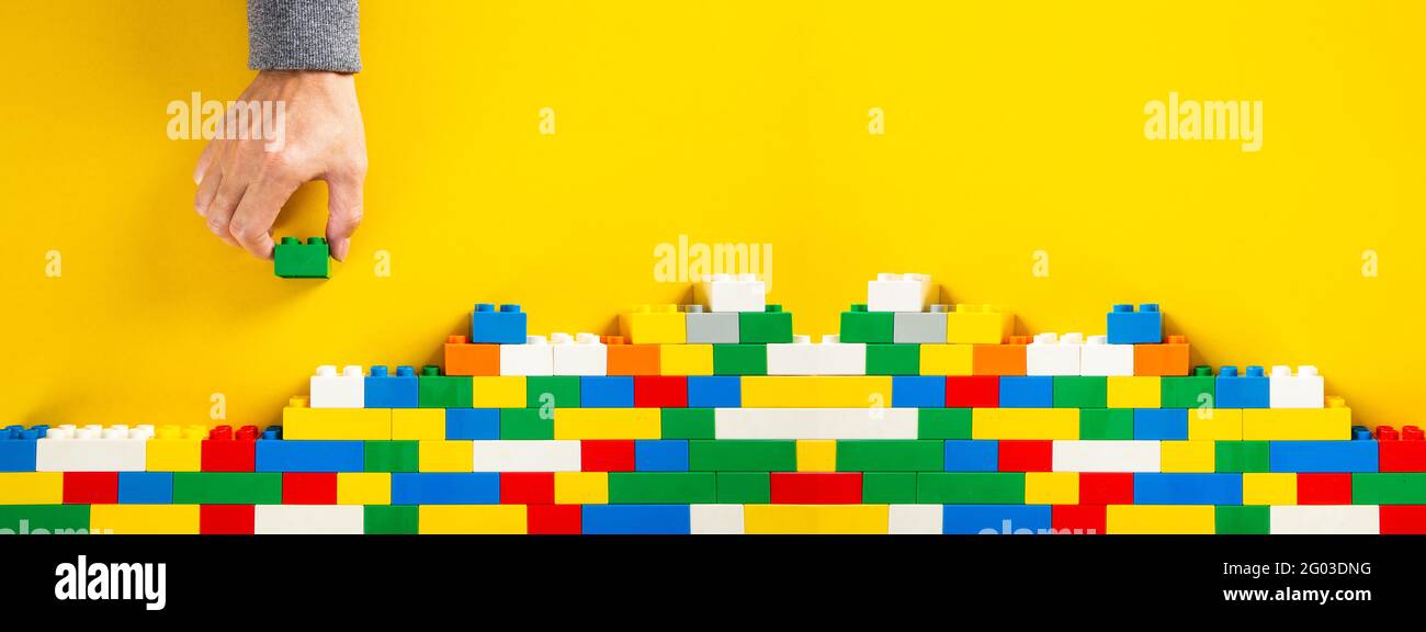 Hand Stack Wall Blocks hand building up a wall by stacking up colorful plastic block Stock ...