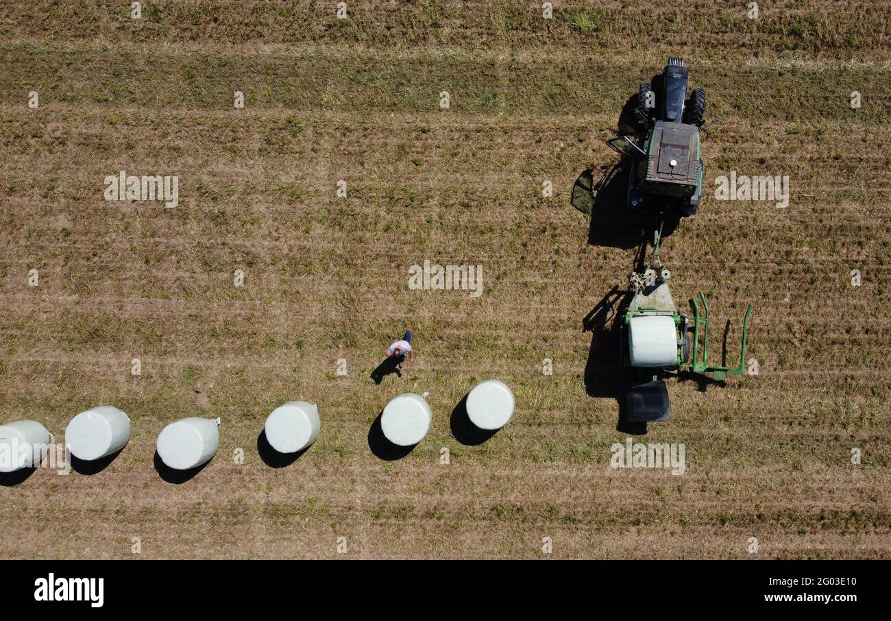 A farmer speaks on his mobile device after wrapping hay bales in a field ahead of a Swiss vote on June 13 on two popular initiatives to curb the use of pesticides in agriculture, in Penthaz, Switzerland, May 31, 2021. Picture taken with a drone. REUTERS/Denis Balibouse Stock Photo