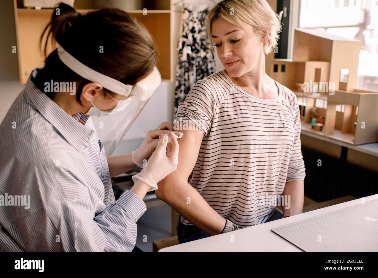 Female nurse injecting medicine to blond woman at home Stock Photo