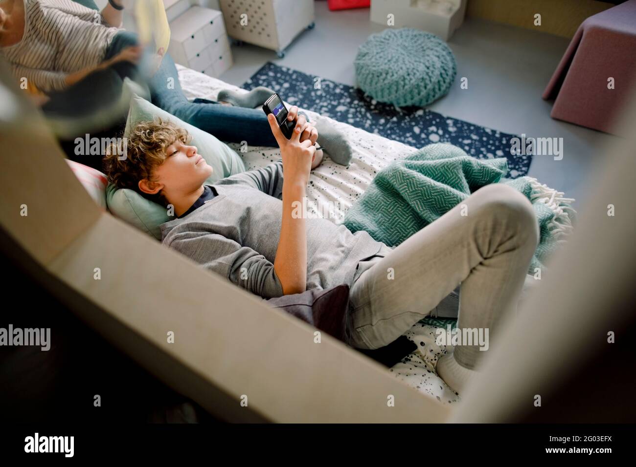 Boy lying on bed wile using smart phone Stock Photo
