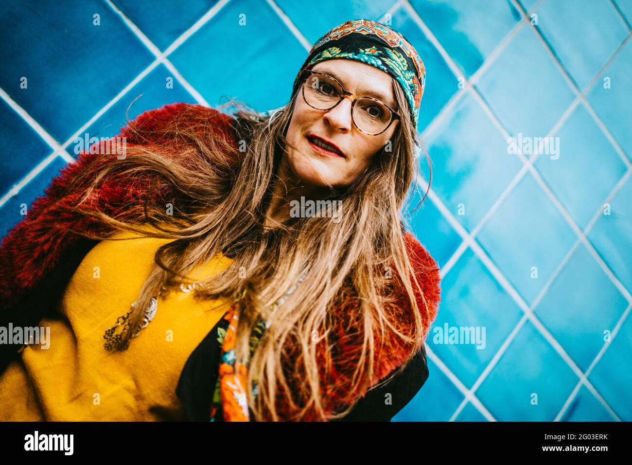 Portrait of mature woman wearing headscarf against blue tiled wall Stock Photo