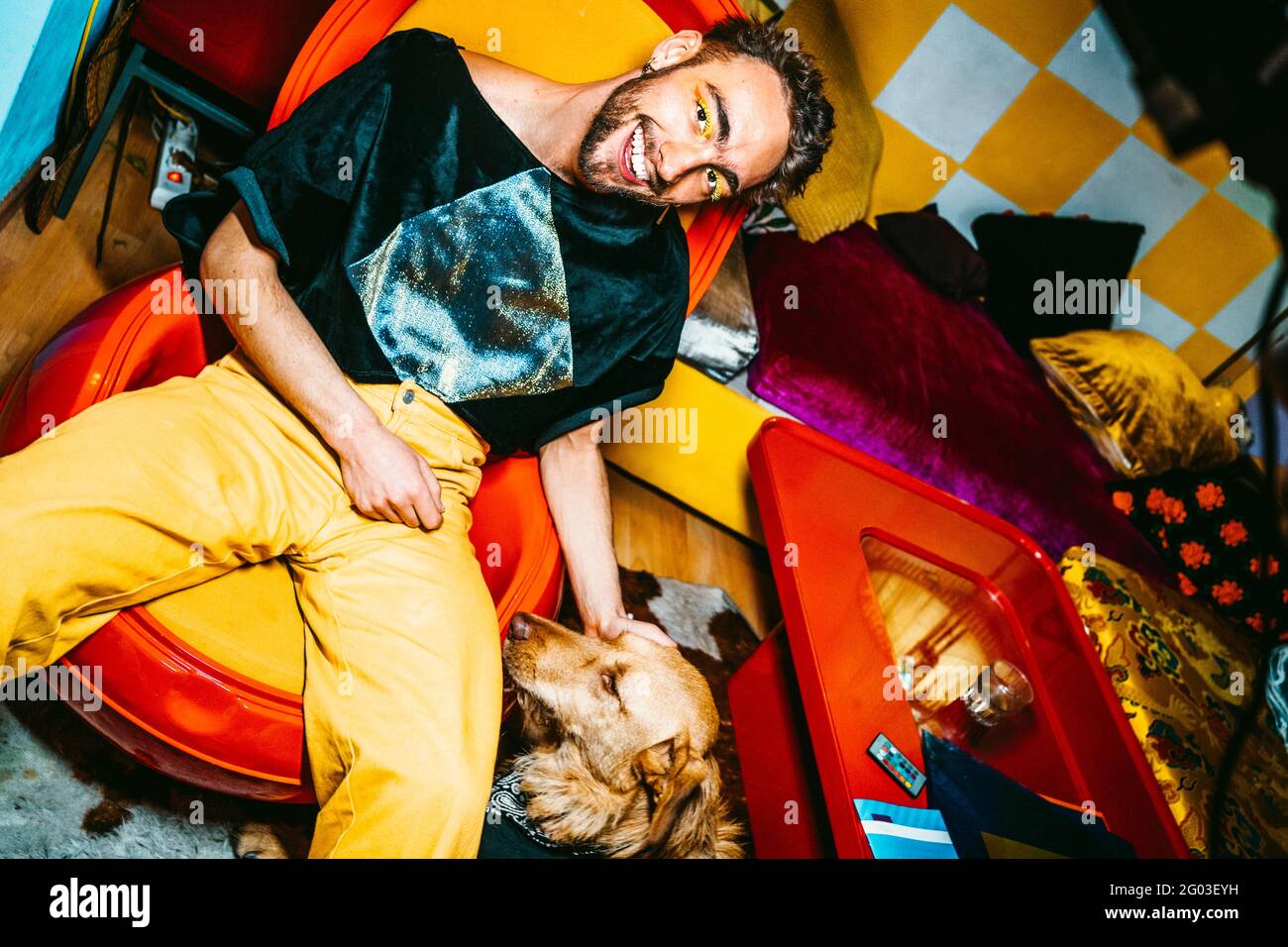 Portrait of smiling young man with dog in living room Stock Photo