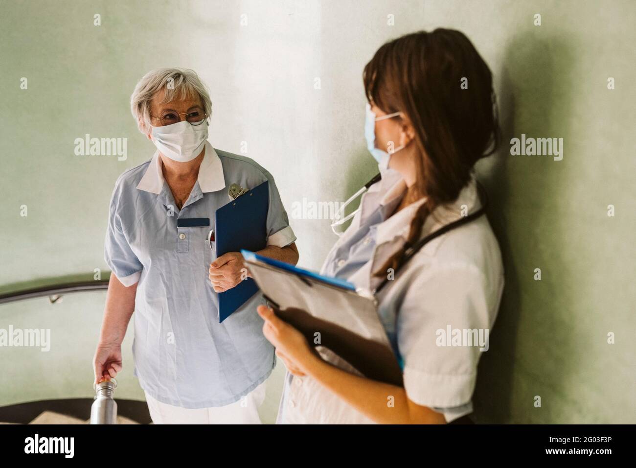 Female healthcare workers wearing face mask discussing at medical