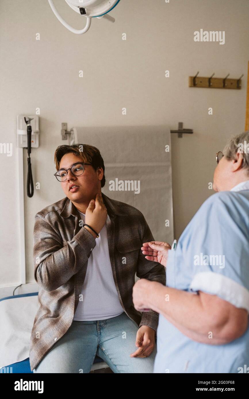 Senior female doctor examining young male patient at medical clinic Stock Photo