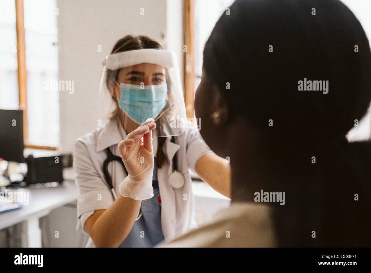 Female medical expert doing patient's medical test during COVID-19 Stock Photo