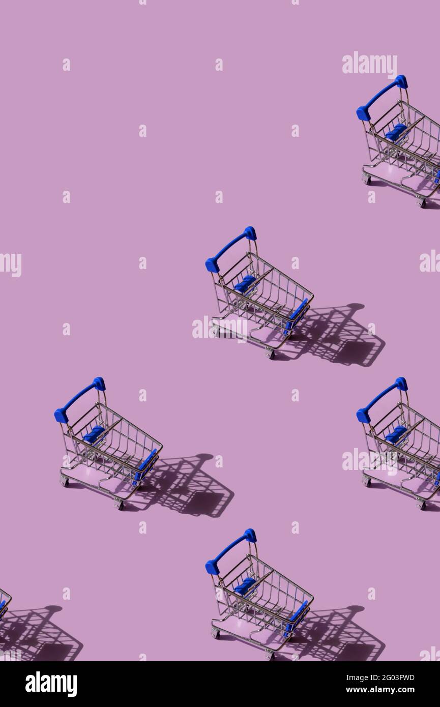 Miniature supermarket trolley pattern on pink background. Place for text. Stock Photo