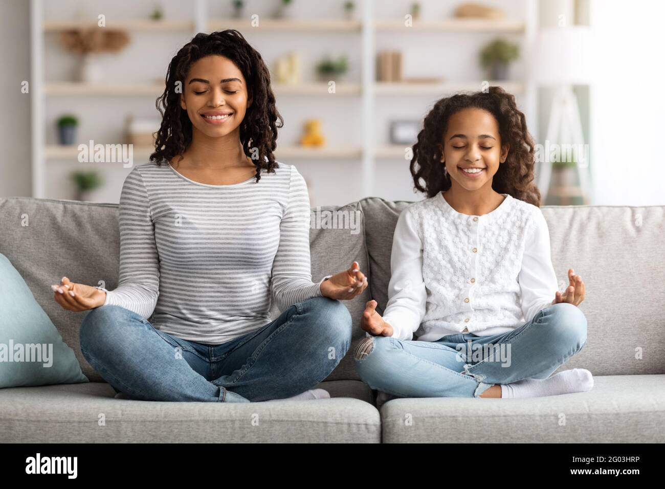 Relaxed black mother and daughter sitting on couch, meditating Stock ...