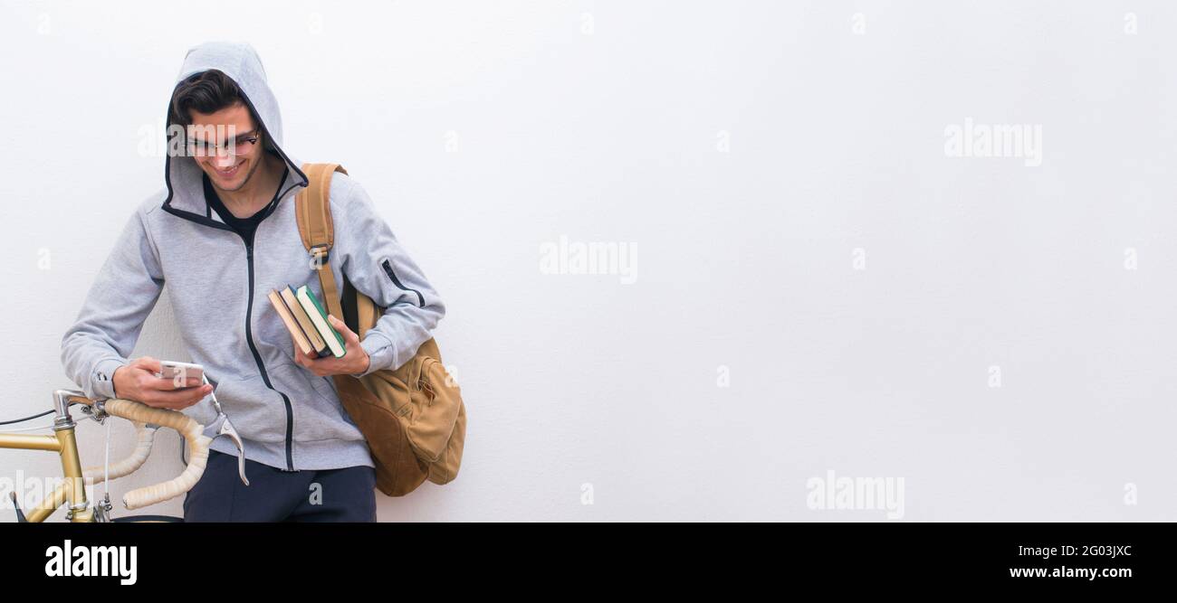 student with cellphone and bicycle on white wall background Stock Photo