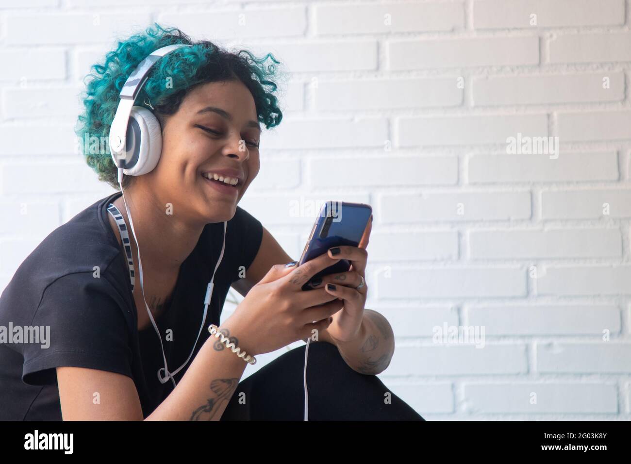 portrait of young woman with mobile phone and headphones listening to music Stock Photo