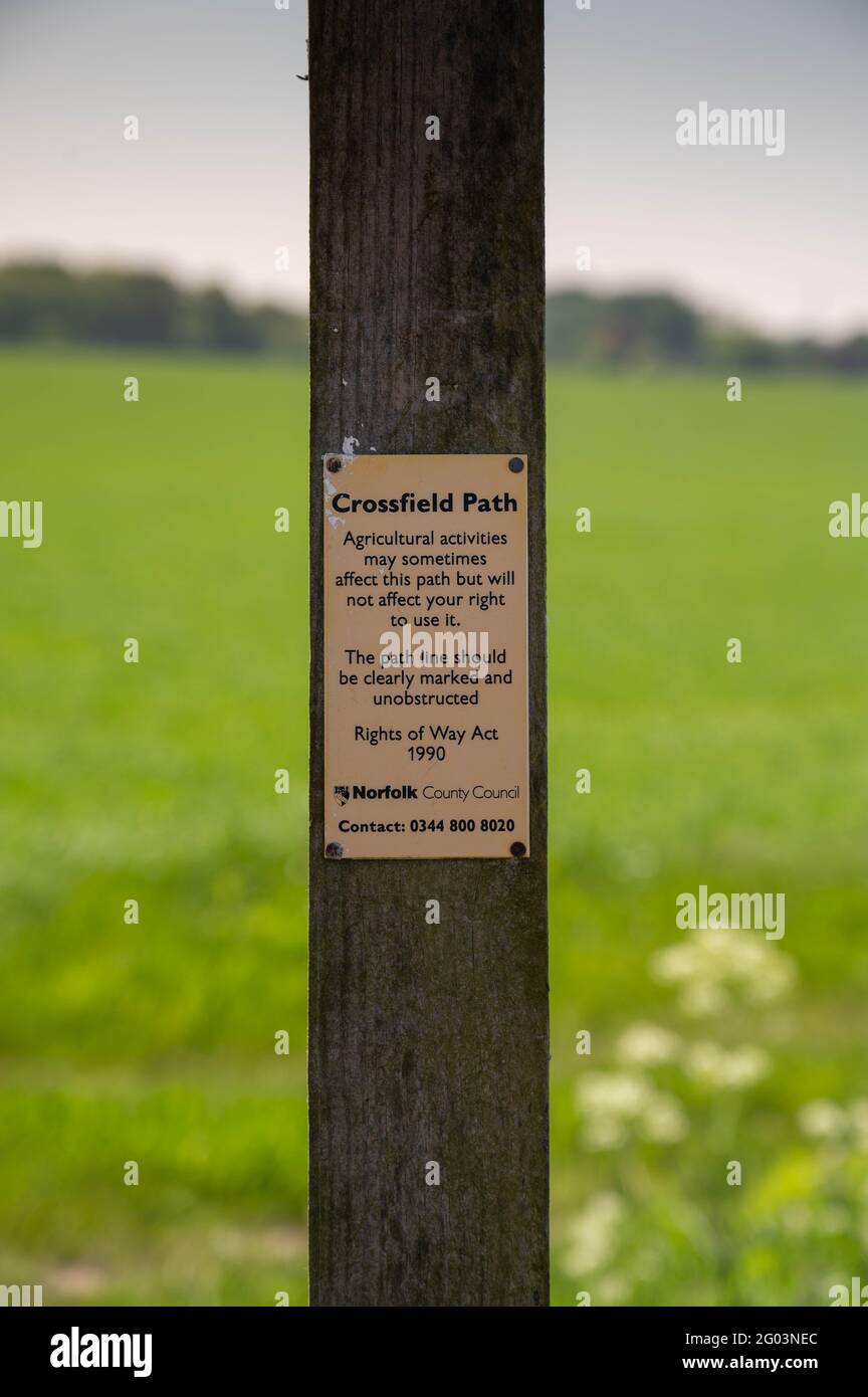A cross field path sign on the corner of a countryside farmers field stating right of way across field Stock Photo