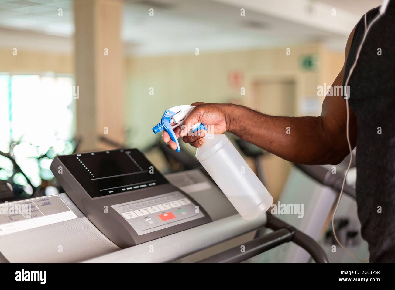 Close up of a person cleaning a gym machine with disinfectant. Selective focus. Space for text. Stock Photo