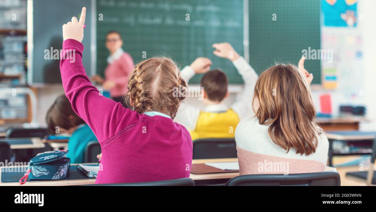 Two girl students raising hands to answer a question in school class Stock Photo