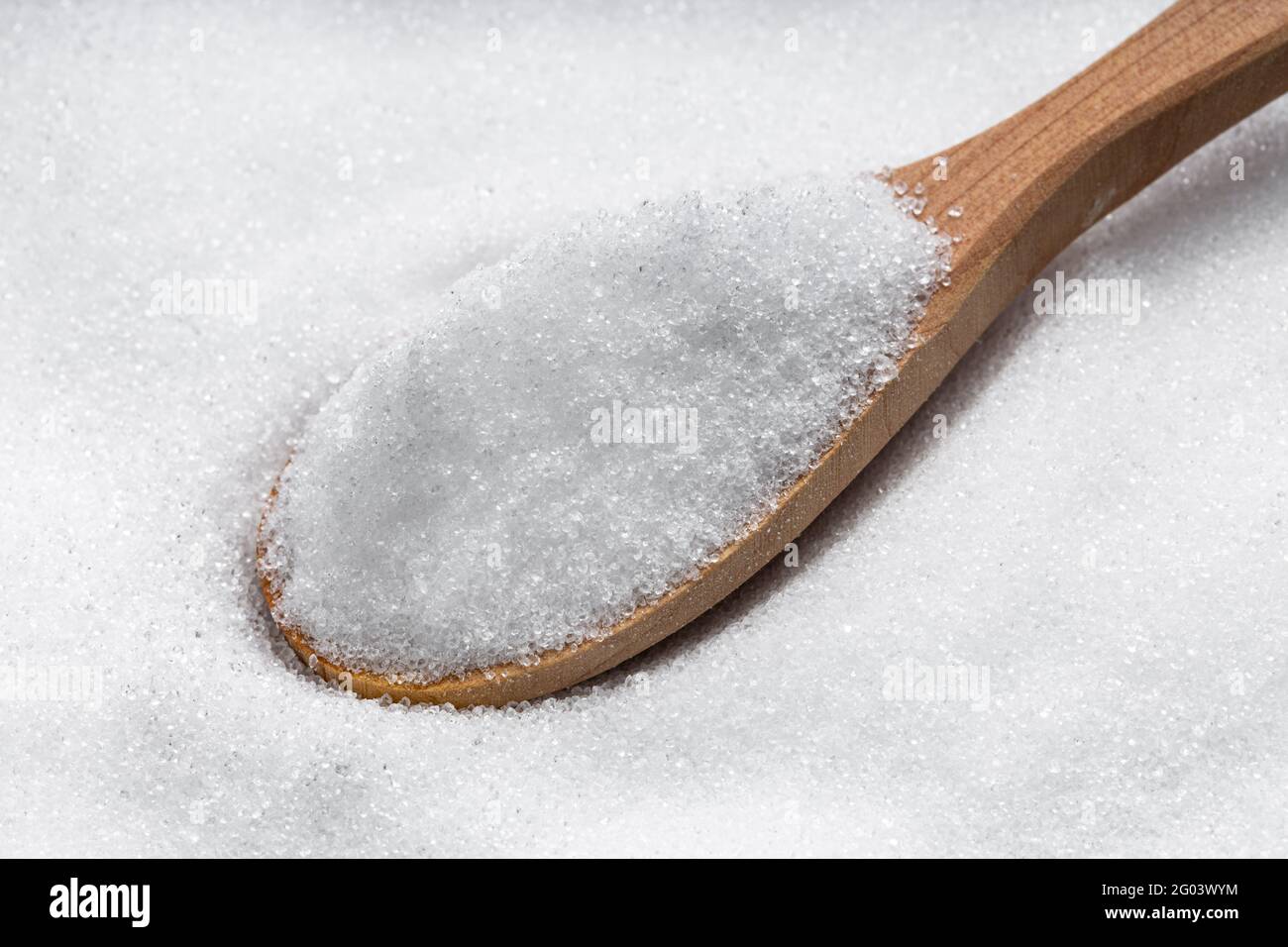 above view of wooden spoon with crystalline erythritol sugar substitute close up on pile of sugar Stock Photo