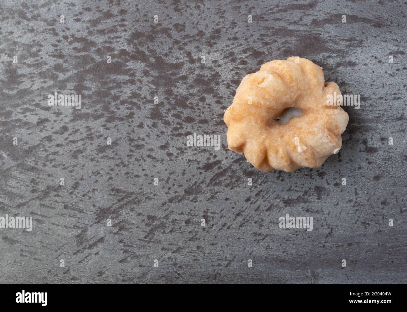 Top view of a cruller shaped donut on a mottled gray background. Stock Photo