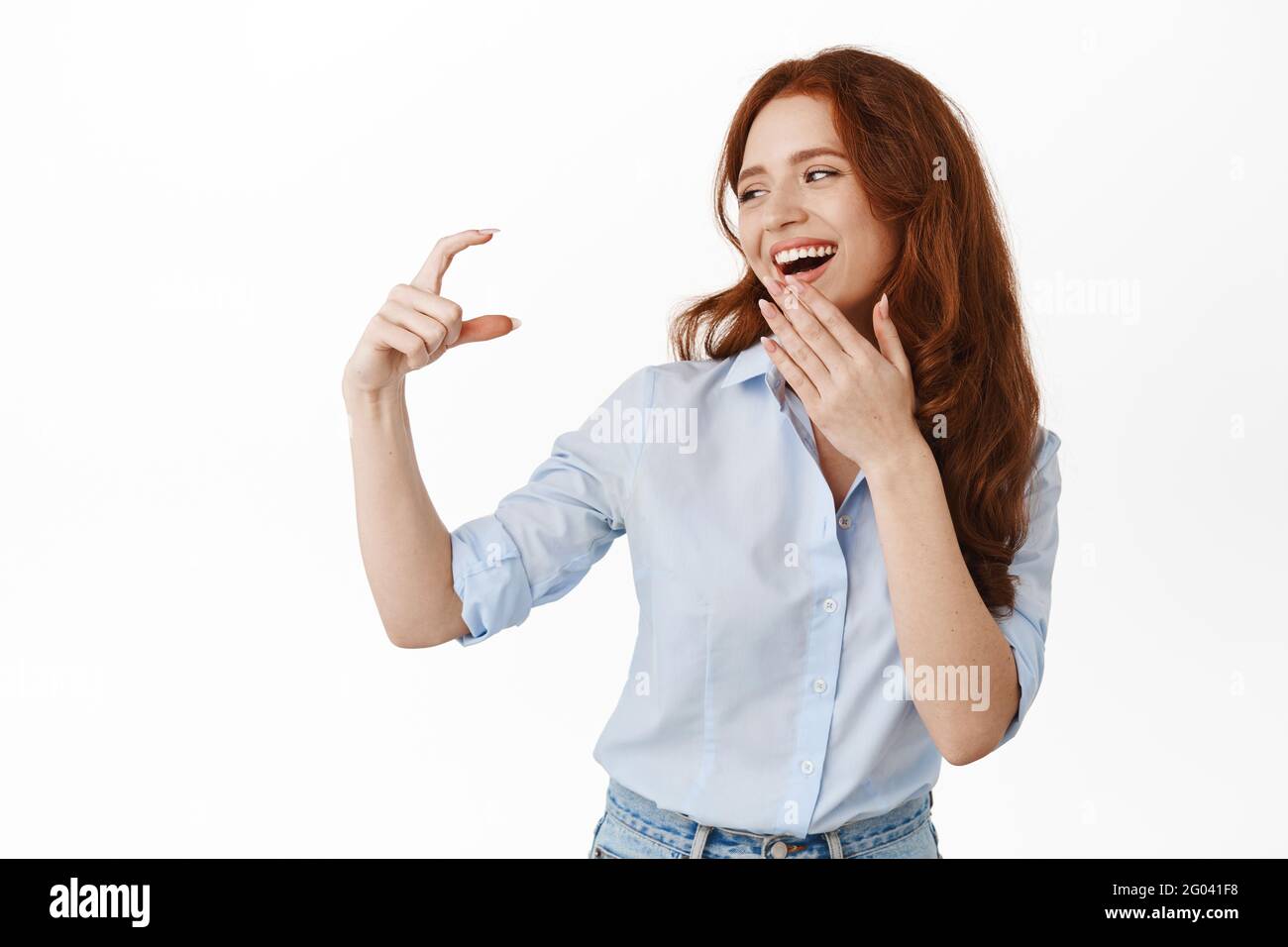 Happy female model looking at small tiny thing, showing little hand ...