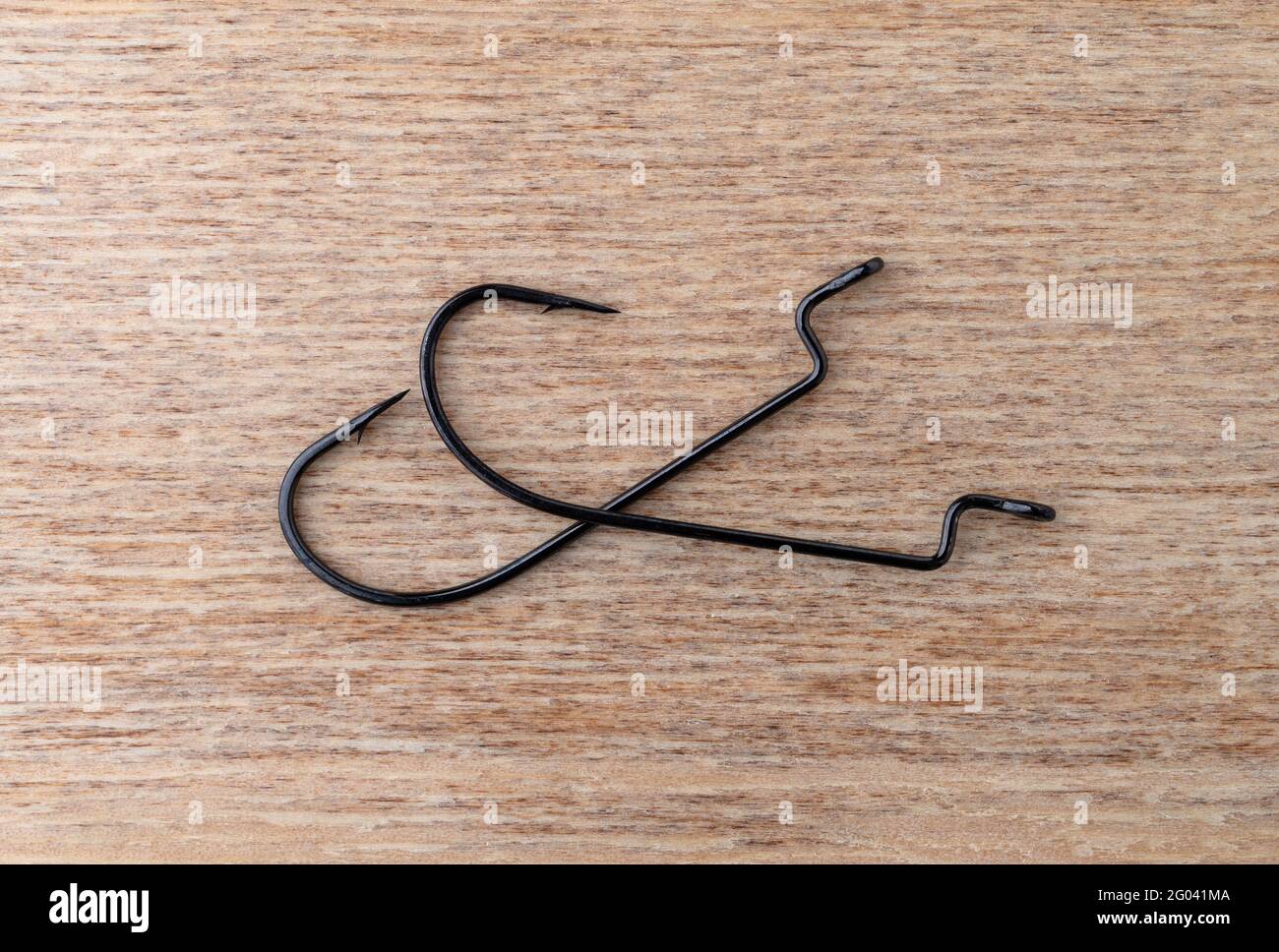 Top view of two offset plastic worm bait hooks on a wood