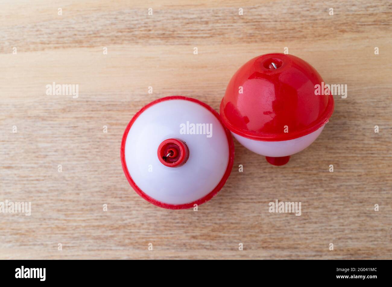 Top view of two red and white plastic fishing bobbers on a wood