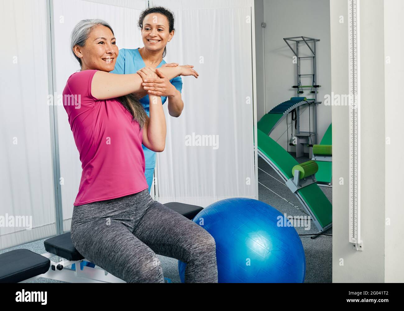Mature female patient while exercise treatment with her physiotherapist. Rehab at a medical center Stock Photo