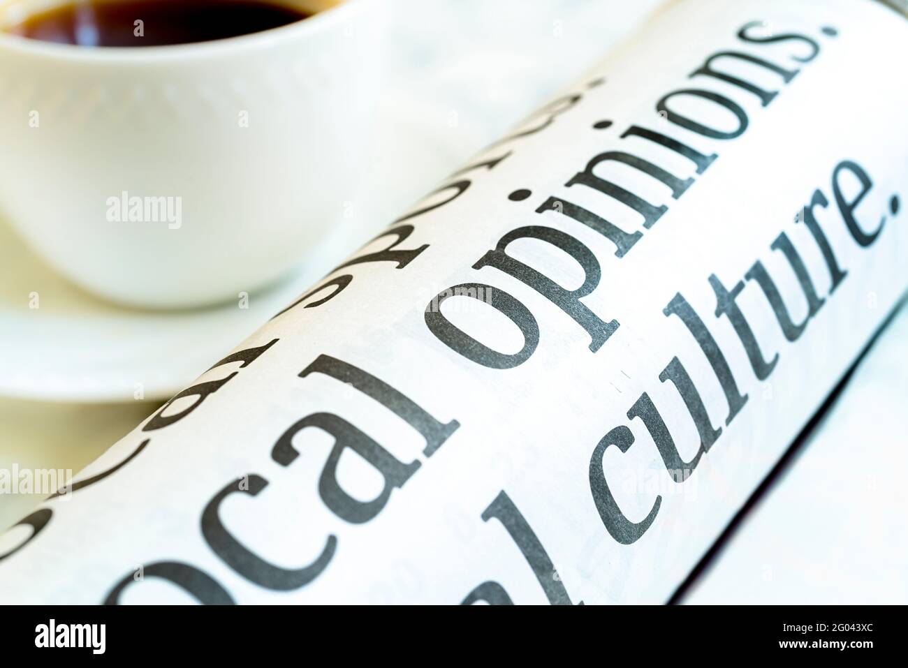 Rolled up morning paper along side a cup of coffee. Stock Photo