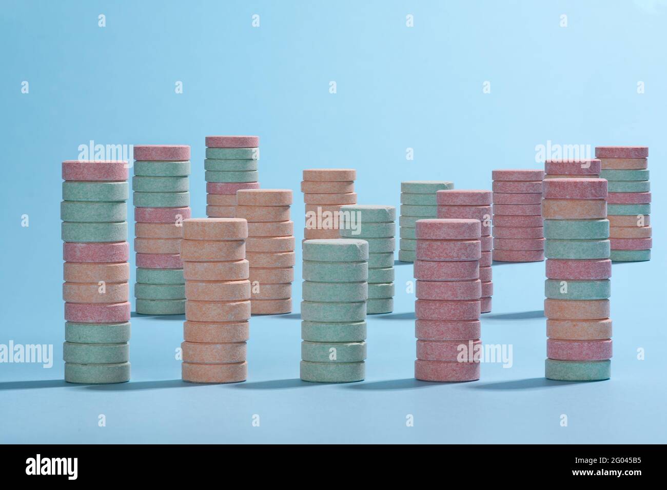 Army of columns of colourful pink, orange and cyan tablets placed on a light blue background Stock Photo